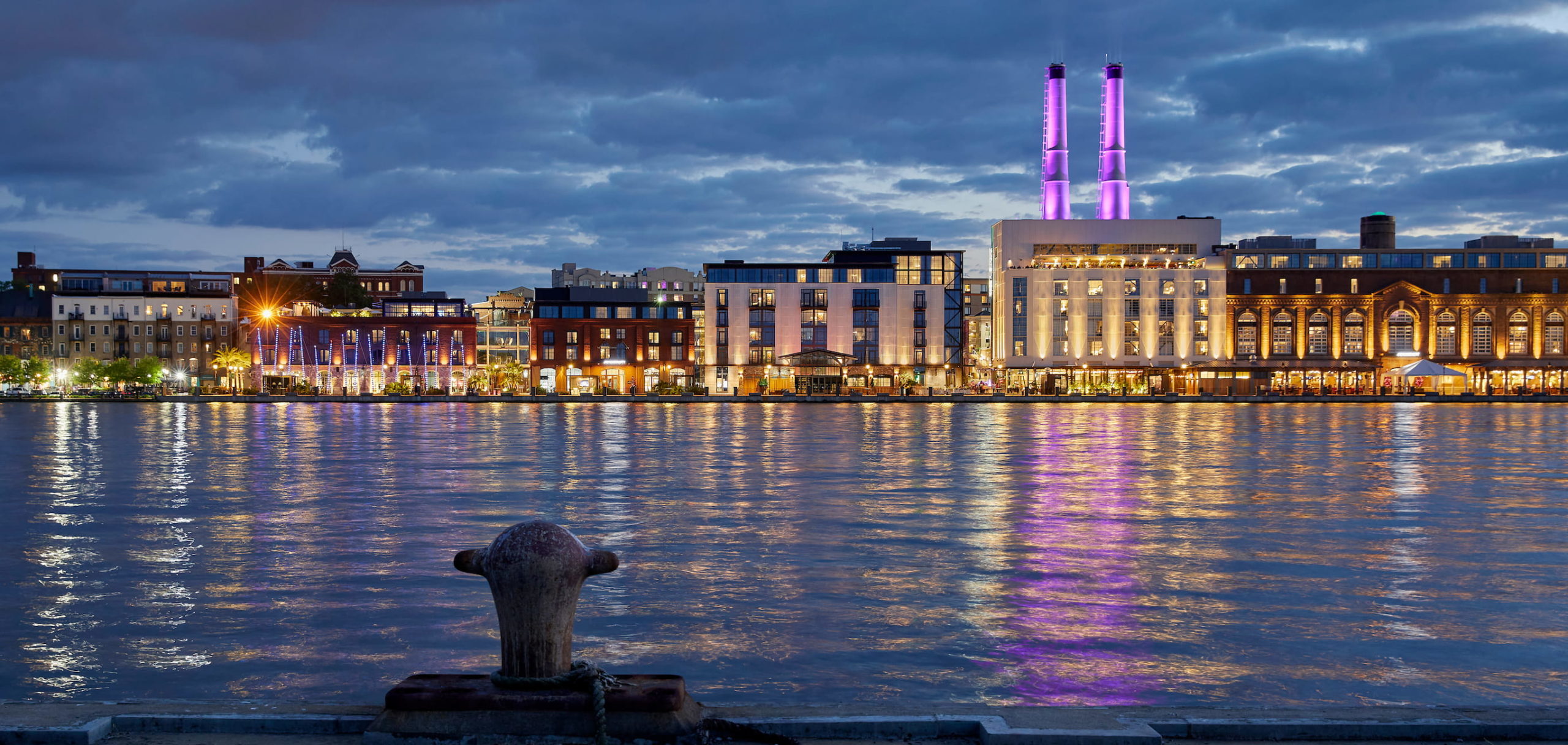 Savannah Georgia downtown skyline at night with illuminated historic buildings and street lights reflecting urban landscape